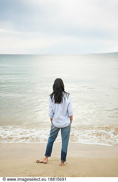 Woman spending leisure time standing near shore at beach