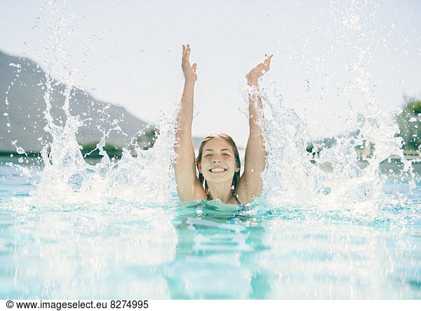 Woman splashing in swimming pool