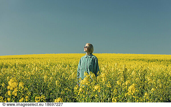 Woman standing amidst flowers in rapeseed field