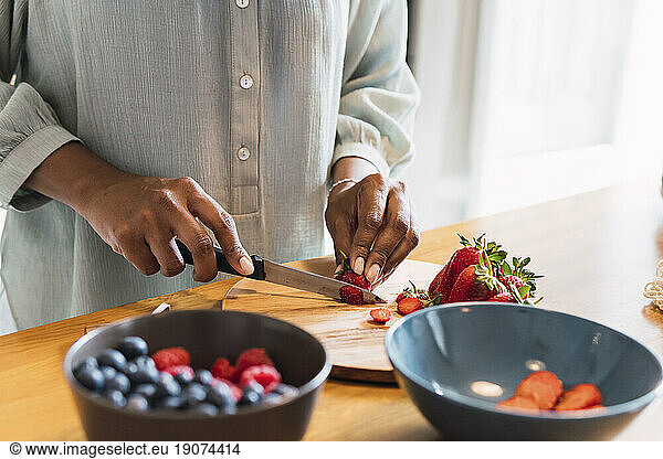 Woman standing at kitchen counter chopping healthy food
