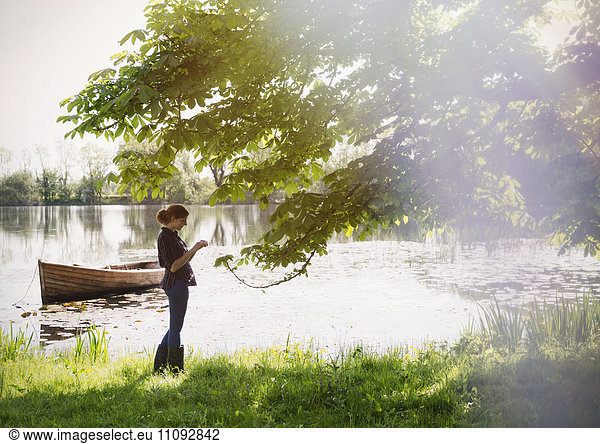 Woman standing at sunny idyllic lakeside
