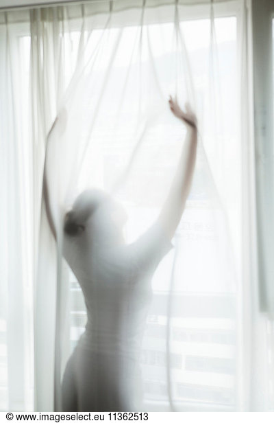 Woman  standing behind curtain  stretching  morning