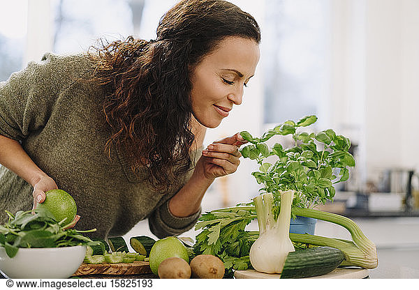 Woman standing in kitchen,  smelling ingredients for healthy smoothie
