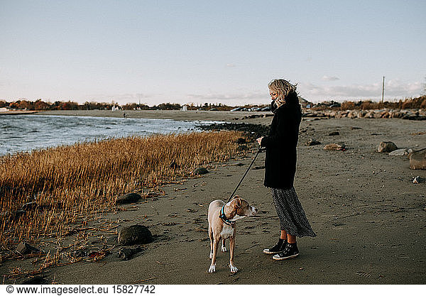 woman standing on beach with dog in wintertime