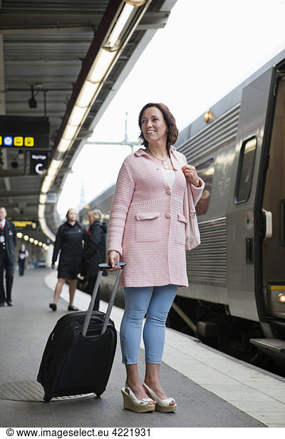 Woman standing on platform with suitcase