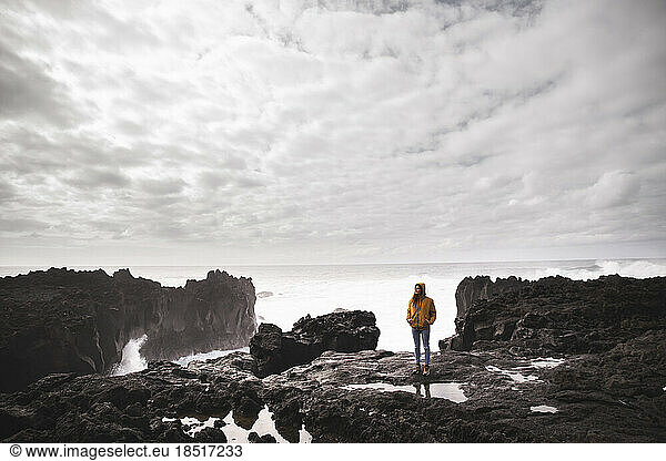 Woman standing on rock in front of sea