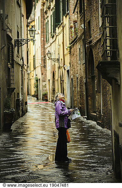 Woman standing on street after rain  Lucca  Tuscany  Italy
