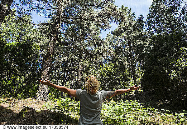 Woman standing with arms outstretched in forest