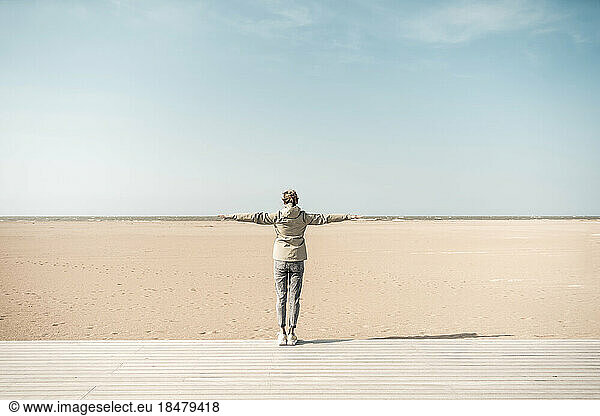 Woman standing with arms outstretched on beach