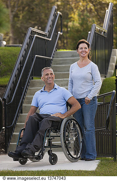 Woman standing with husband in wheelchair with spinal cord injury on accessible ramp