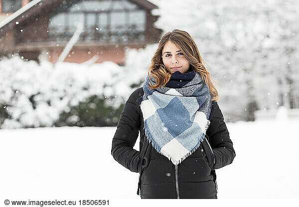 woman stands against the background of the snowy yard of her home