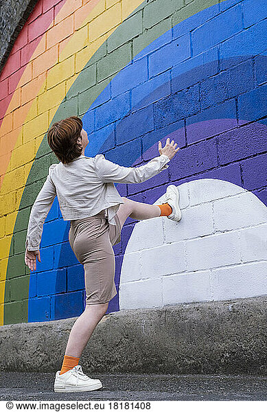 Woman stepping on rainbow colored wall