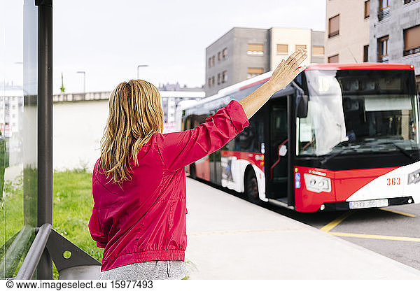 Woman stopping bus at bus stop