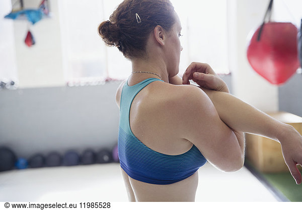 Woman stretching arm and shoulder in gym