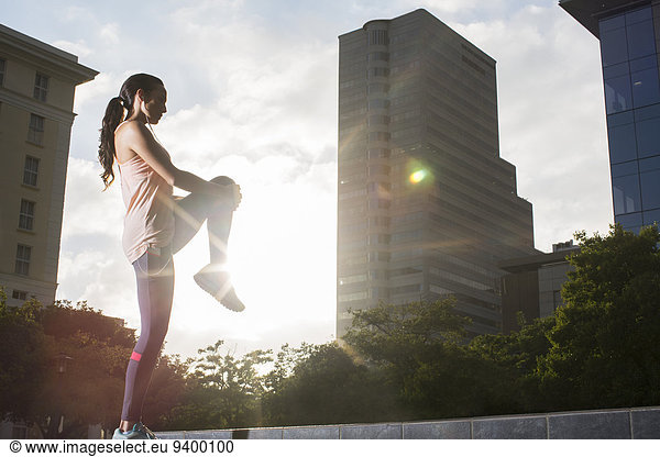 Woman stretching before exercising on city street