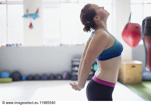 Woman stretching chest in gym