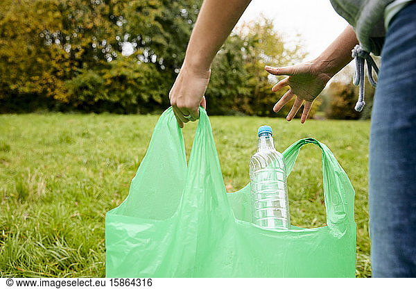 Woman stuffing soft waste plastics into large plastic bottle to make an ecobrick for use as a building block