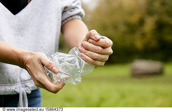 Woman stuffing soft waste plastics into large plastic bottle to make an ecobrick for use as a building block