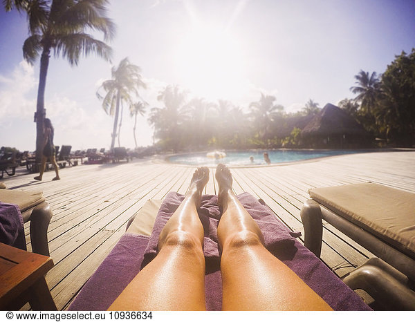 Woman sunbathing at sunny tropical poolside