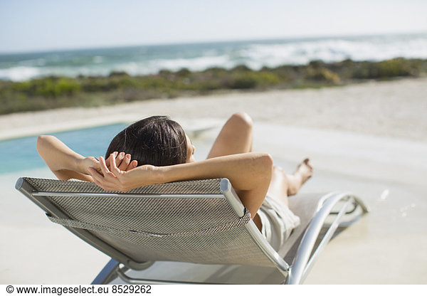 Woman sunbathing on lounge chair at poolside