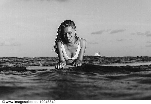 Woman surfer on a surfboard in the ocean waiting for the waves.