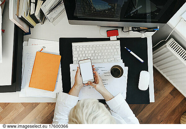 Woman surfing net through smart phone on desk