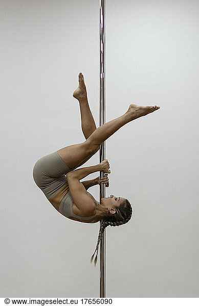 Woman suspended dancing on pole dance sport school