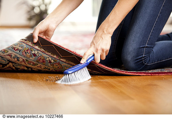 Woman sweeping under the carpet