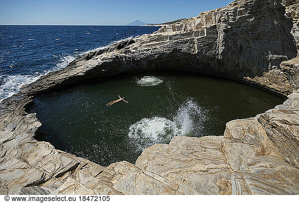 Woman swimming in cave pool on sunny day
