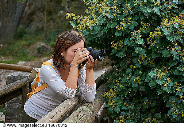 Woman takes pictures with her camera supported by a wooden bridge