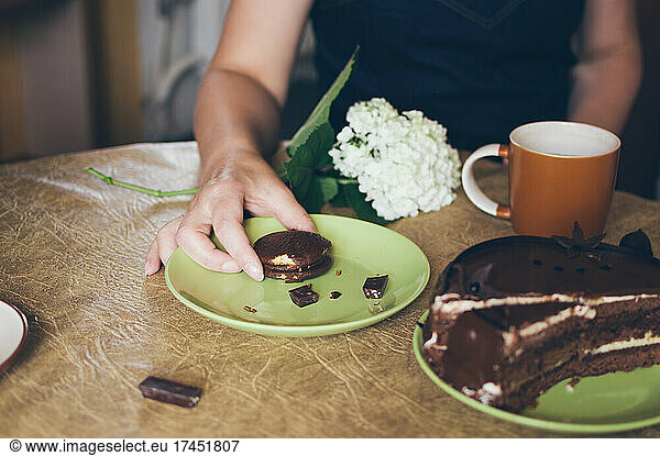 Woman takes small round chocolate cake during tea party