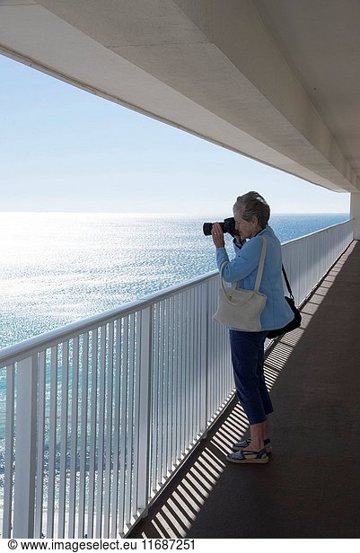 Woman taking a photo of the Gulf coastline from a high rise balcony