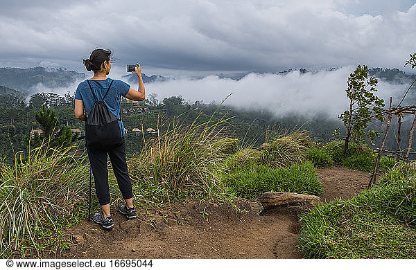 woman taking a picture at the top of Adam's Peak close to Ella