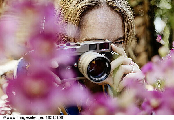Woman taking photo through camera in garden