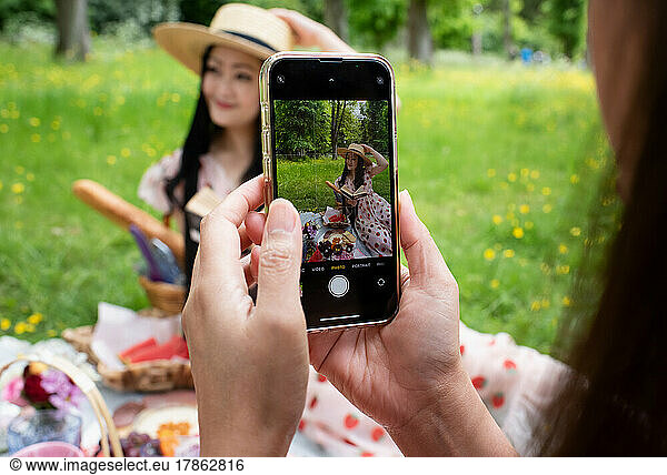 woman taking pictures of her friend with a mobile phone