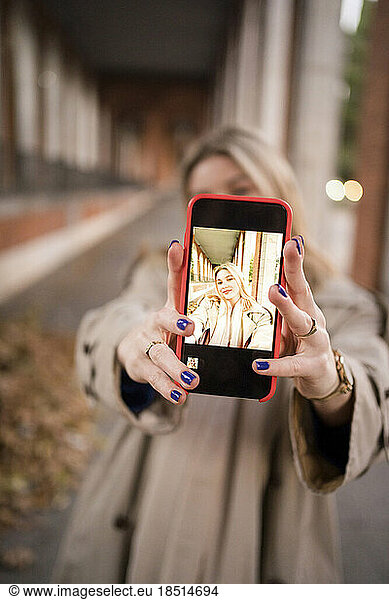 Woman taking selfie through smart phone screen