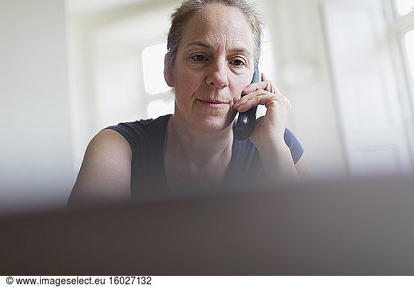 Woman talking on telephone and working at laptop