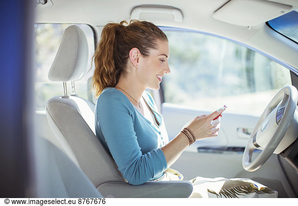 Woman texting with cell phone inside car