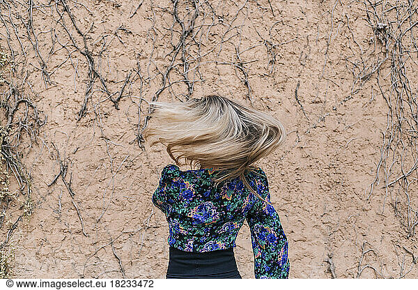 Woman tossing hair dancing in front of wall