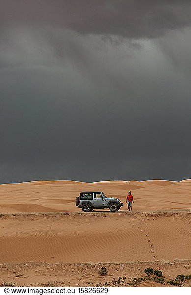 woman tourist gets out of jeep in the stormy sand dunes of utah