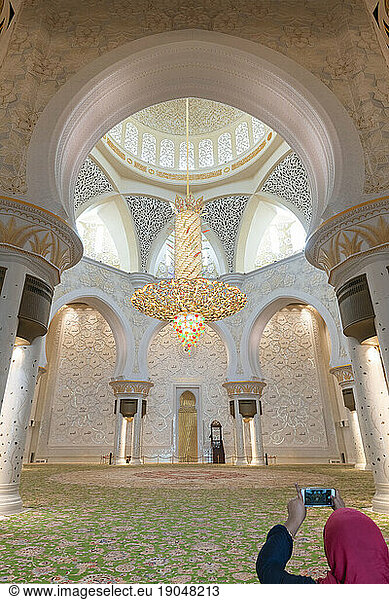 Woman tourist taking photo in central prayer hall  Sheikh Zayed Mosque