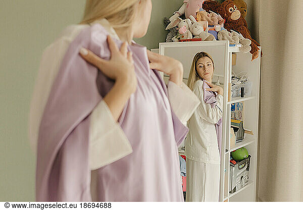 Woman trying dress looking in mirror at home