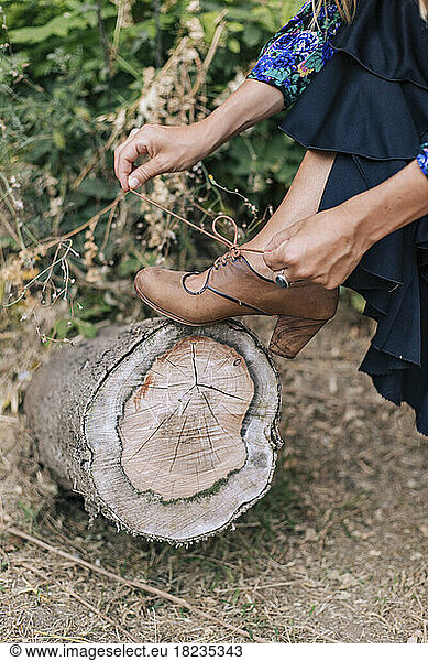 Woman tying shoelace keeping leg on tree stump