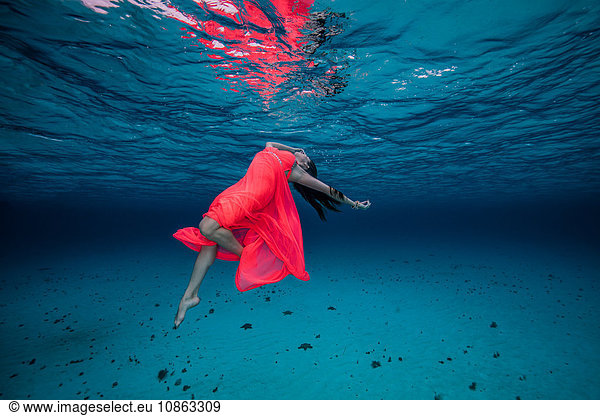 Woman underwater in red dress