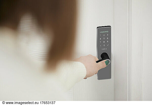 Woman unlocking smart door of house with access of fingerprint