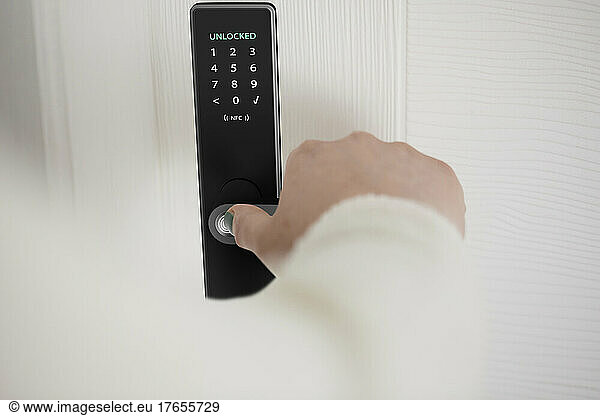 Woman unlocking smart door of house with fingerprint