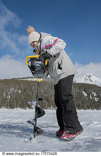Woman using an auger on the ice