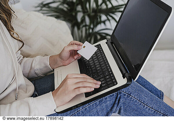 Woman using credit card for payment through laptop