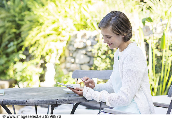 Woman using digital tablet at table outdoors