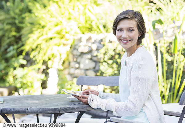 Woman using digital tablet at table outdoors